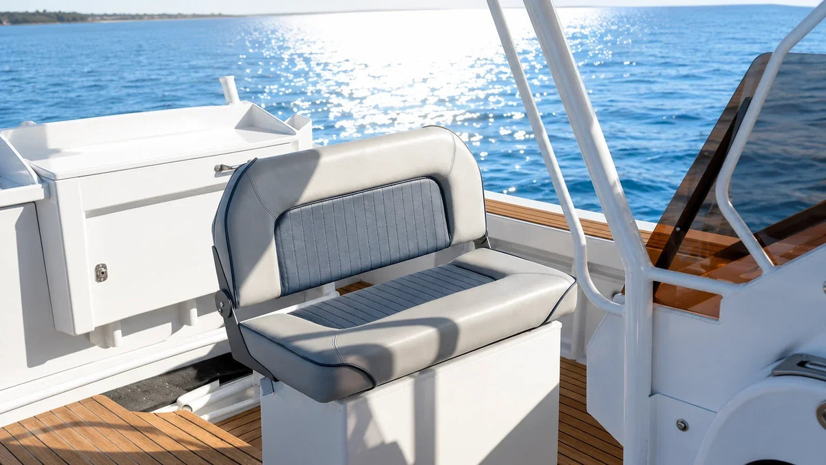 Gray and blue marine bench seat installed on a white boat deck with the ocean in the background.