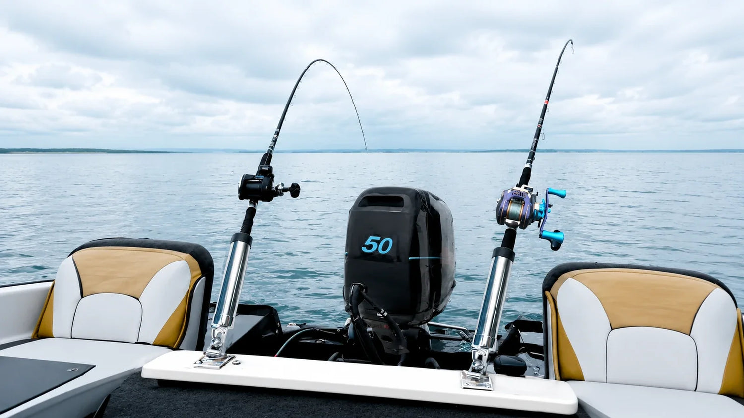 Two fishing rods secured in stainless steel rod holders at the stern of a motorboat on a calm lake.