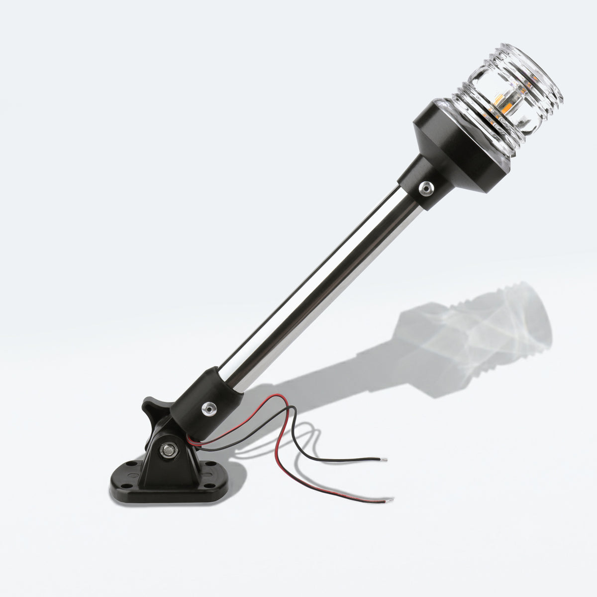 Marinexplore 12-inch black anchor light with an extended pole and clear ribbed lens glowing warm white, mounted on a folding black base with red and black wire leads, photographed at an angle on a light gray studio backdrop.