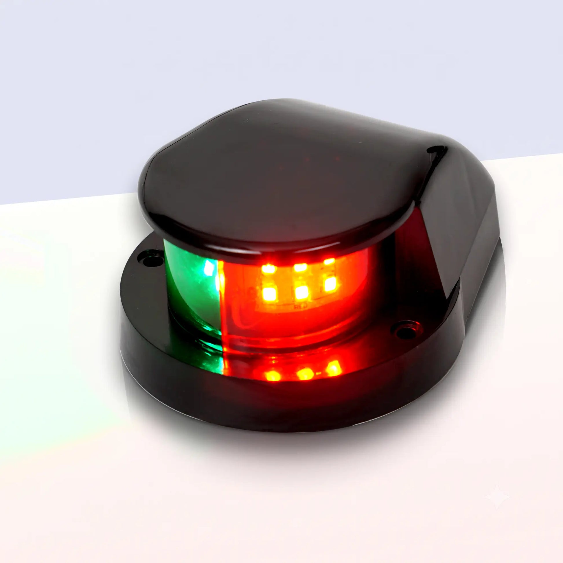 Marinexplore black ABS boat bow navigation light with a teardrop-shaped dome housing and two mounting screw holes on the black base, photographed at a three-quarter angle showing the illuminated green and red bicolor lens against a light gray studio backdrop.