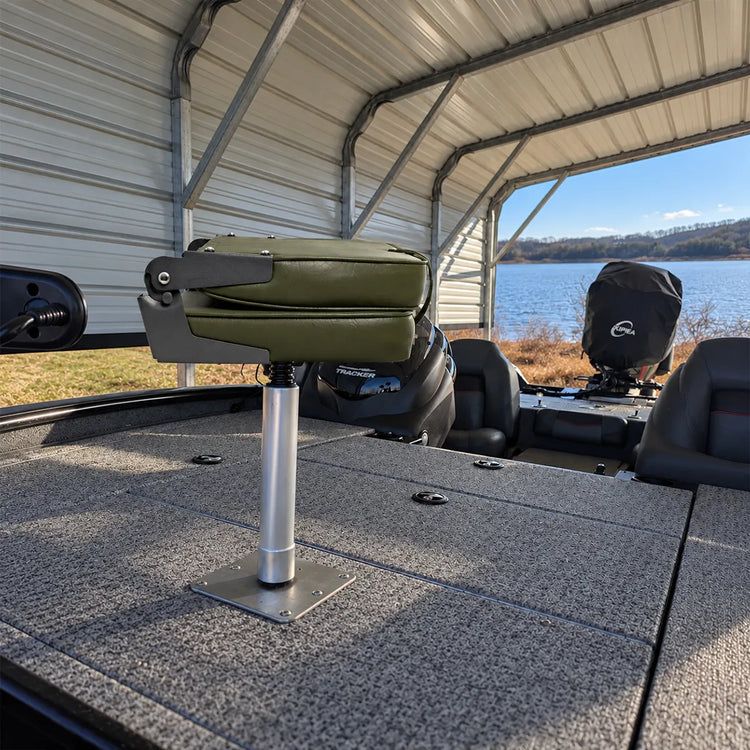 Customer-installed green fold-down fishing seat on a tall silver boat seat pedestal beside a lake.