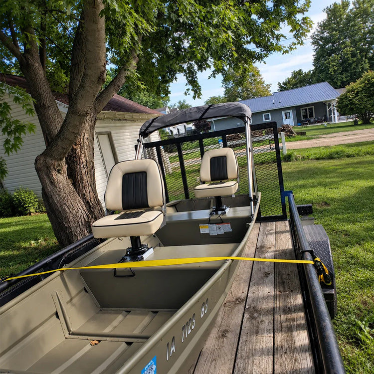 Customer-installed beige captain's seats on boat seat pedestals beside the console of a trailered boat.