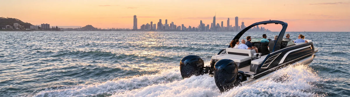 Black pontoon boat with twin outboard motors cruising toward a city skyline at sunset.