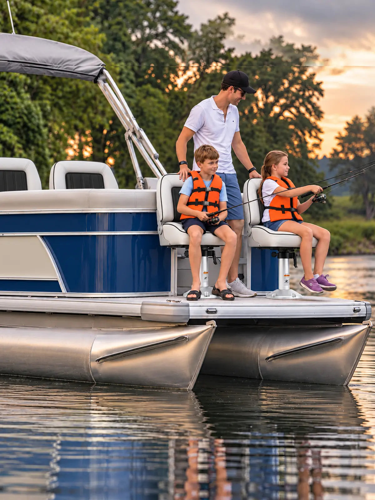 Two children fishing from white pedestal boat seats on a pontoon boat at sunset.