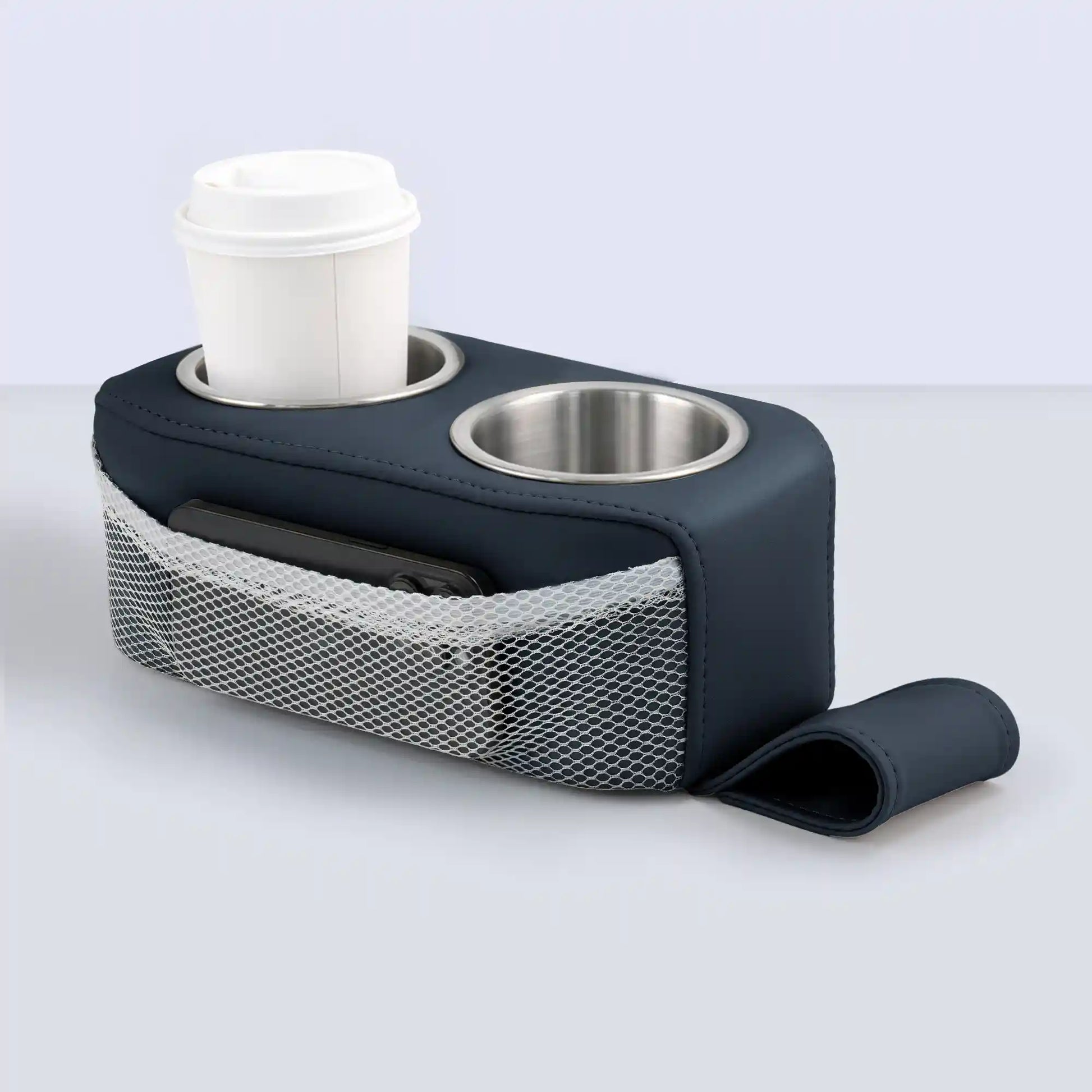 Marinexplore navy blue PU leather pontoon cup holder with two stainless steel inserts, a white takeaway coffee cup in the left slot, a black phone inside the white mesh side pocket, and a matching navy blue anchor strap unrolled in front, shown from a forward angle on a light gray background.